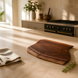 Eaglecreek Boards live edge black walnut wooden board on a kitchen countertop with a linen cloth and rosemary sprig.