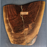Eaglecreek Boards live edge black walnut wooden serving board with rich grain patterns on a blue textured background