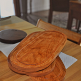 Eaglecreek Boards oval hardwood serving board with juice groove, featuring a smooth natural wood grain finish.
