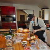 Eaglecreek Boards oval hardwood serving board used by a chef to arrange a charcuterie platter in a kitchen