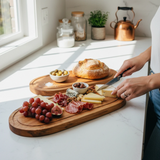 Eaglecreek Boards oval hardwood serving platter with cheese, charcuterie, and grapes on a white kitchen countertop.