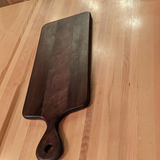 Eaglecreek Boards walnut wood paddle cutting board with a smooth finish, ideal for serving charcuterie.
