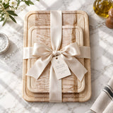 Eaglecreek Boards maple edge grain cutting boards stacked and tied with a cream ribbon as a gift on a marble counter.