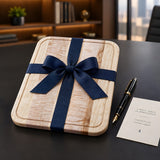 Eaglecreek Boards maple edge grain cutting board wrapped with a navy blue ribbon, displayed as a gift on a desk.