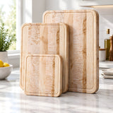 Three Eaglecreek Boards maple edge grain cutting boards in varying sizes standing upright on a marble kitchen counter.