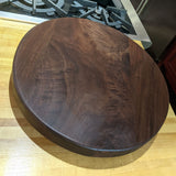 Eaglecreek Boards round dark walnut wood cutting board with natural grain patterns on a kitchen countertop