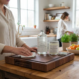 Eaglecreek Boards wood care kit with oil and conditioner on a dark walnut cutting board in a bright kitchen.